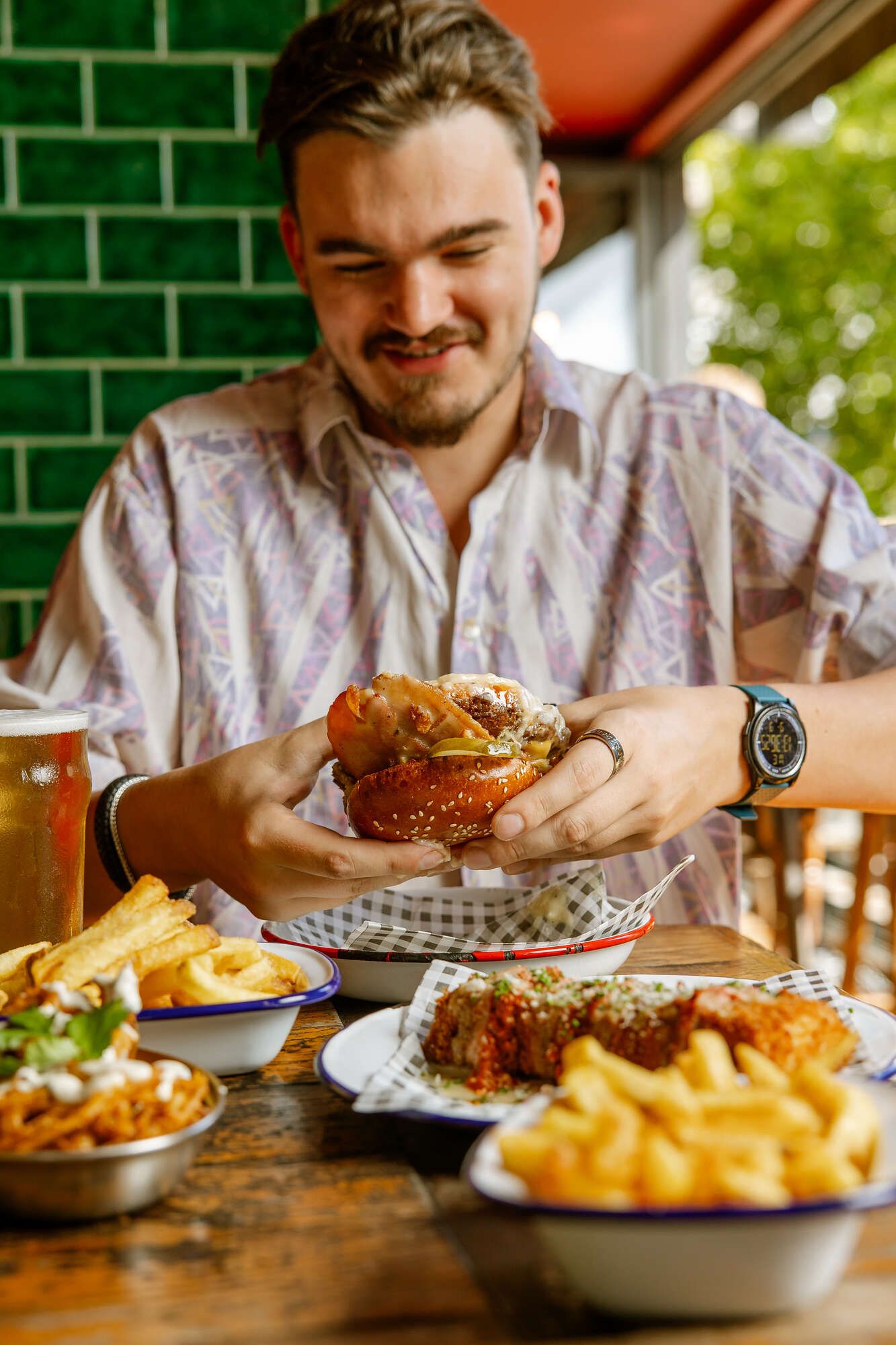 Man eating a burger in the pub with a side