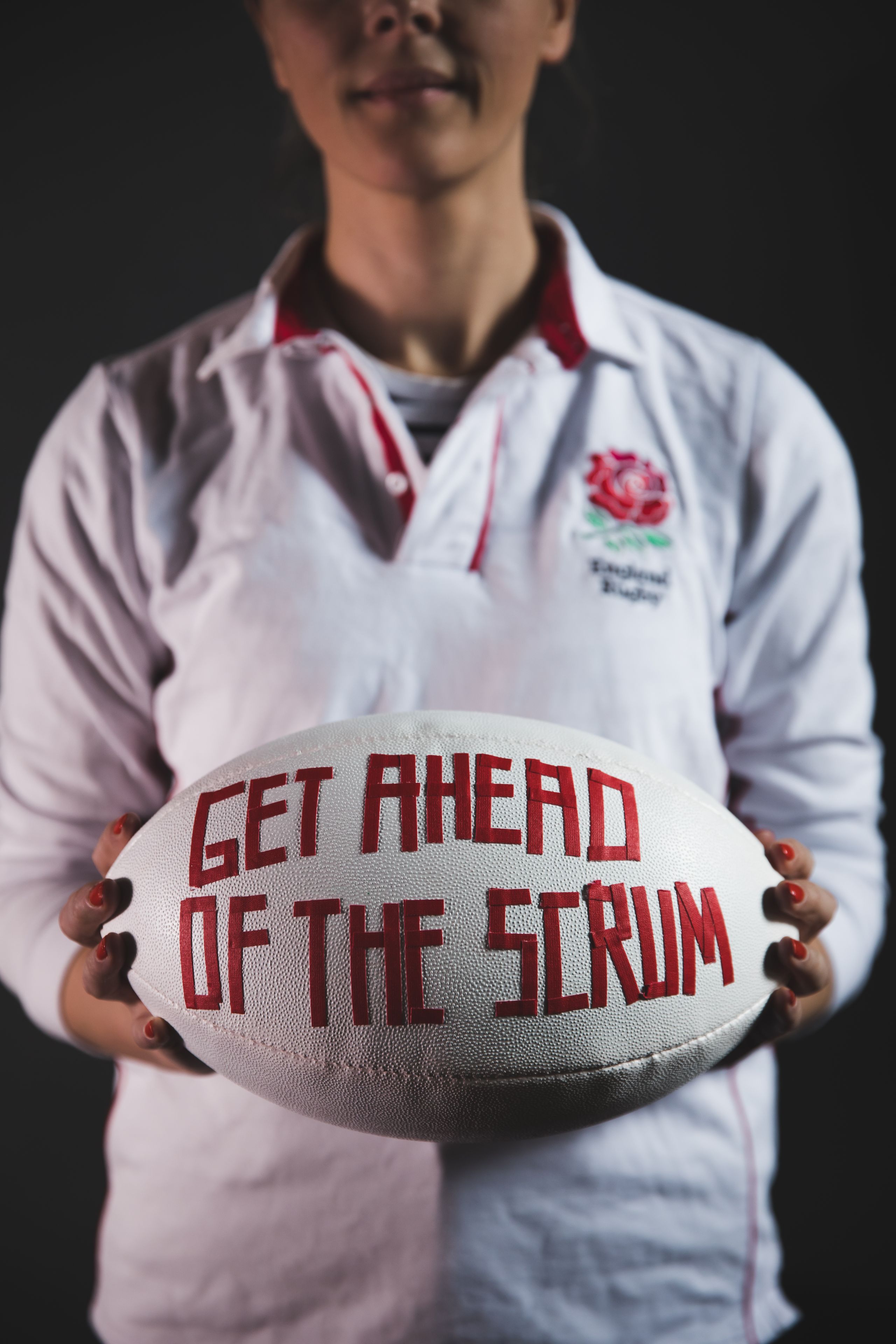 Women holding rugby ball with 'get ahead of the scrum written on it