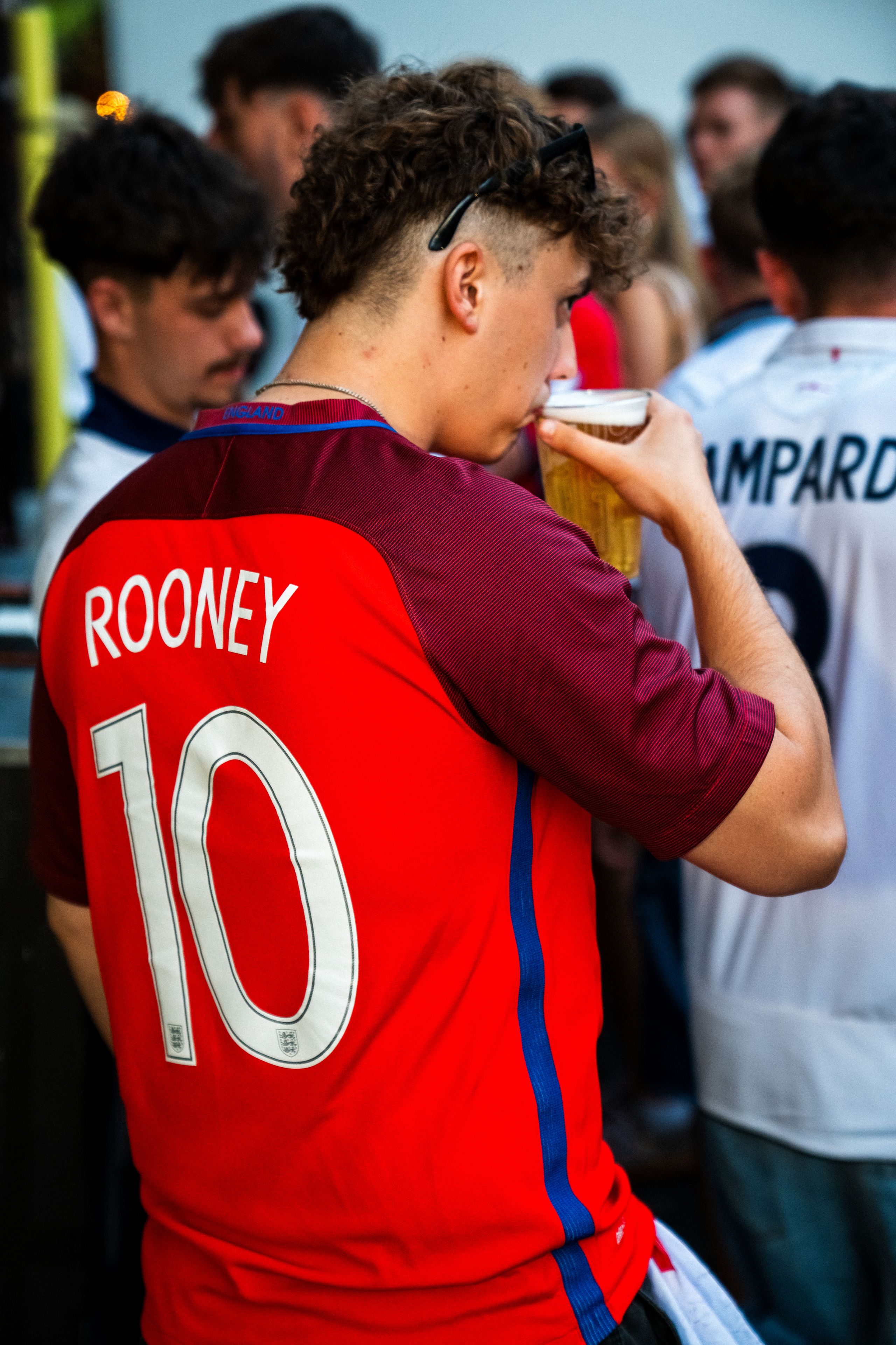 Guy in a Rooney football shirt drinking a pint