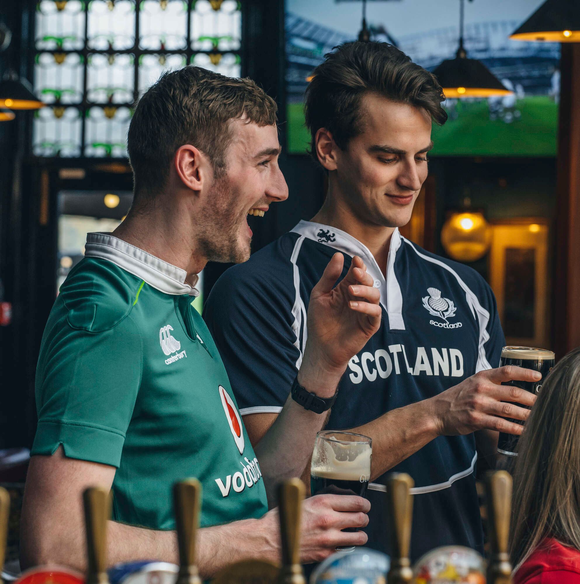 two men watching Rugby eating at the Bar and drinking guinness