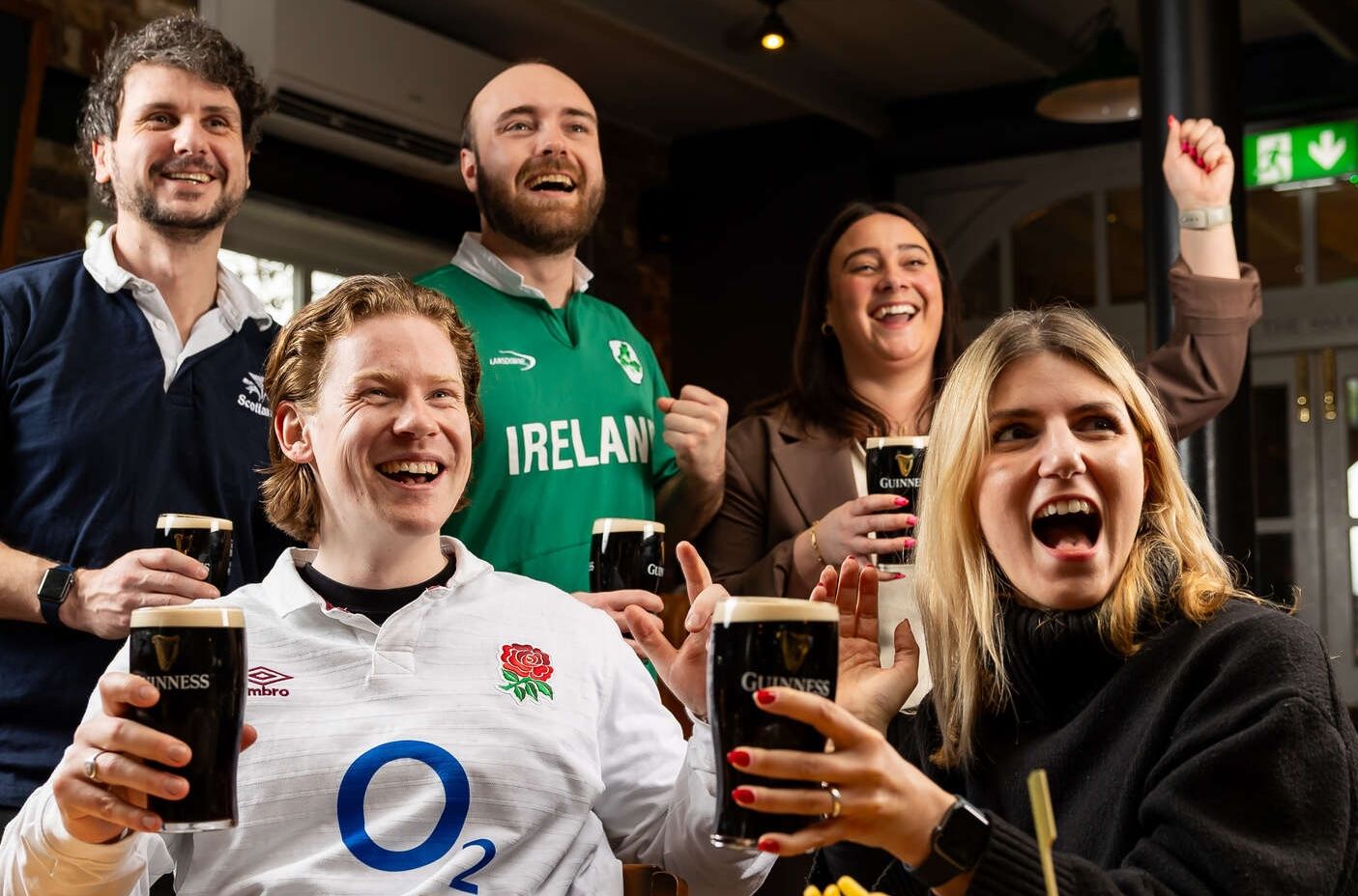Group of friends cheering the Rugby whilst drinking